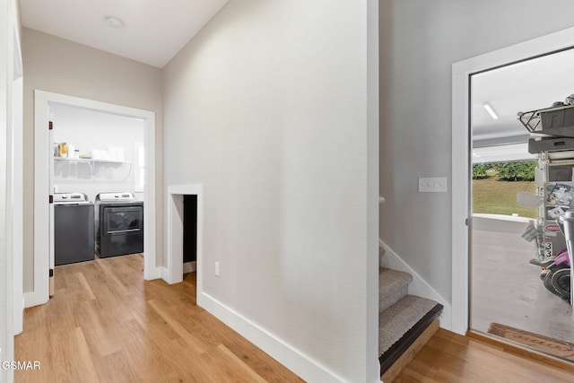 hallway with light wood-type flooring, stairs, baseboards, and washing machine and clothes dryer