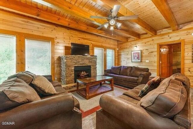 living room featuring ceiling fan, beamed ceiling, wooden walls, a fireplace, and wood ceiling