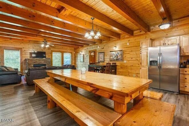 dining space featuring beam ceiling, dark wood-type flooring, wood walls, wood ceiling, and ceiling fan with notable chandelier