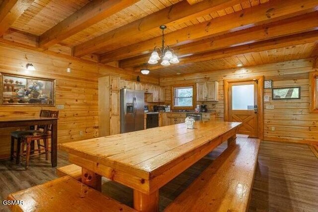 kitchen with dark wood-type flooring, hanging light fixtures, wooden walls, beam ceiling, and stainless steel fridge with ice dispenser