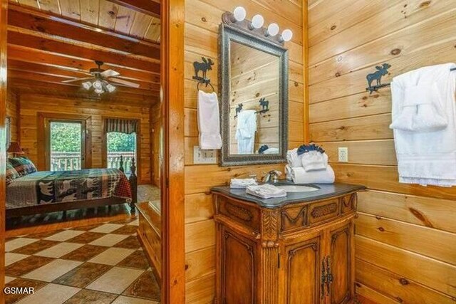 bathroom featuring vanity, wood walls, beam ceiling, and ceiling fan