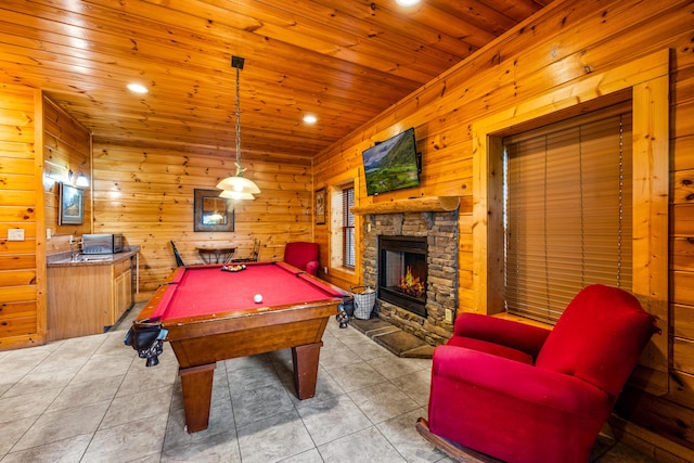 rec room featuring a stone fireplace, wood walls, pool table, wooden ceiling, and light tile patterned floors