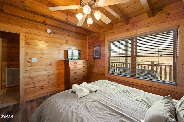 bedroom featuring hardwood / wood-style floors, wooden walls, beamed ceiling, ceiling fan, and wood ceiling