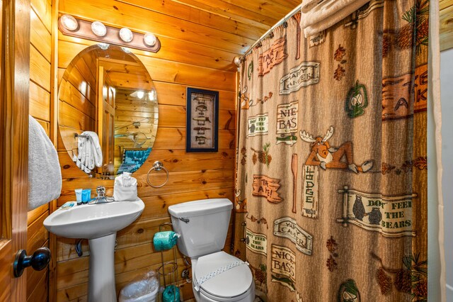 bathroom with a shower with curtain, wooden ceiling, wooden walls, and toilet