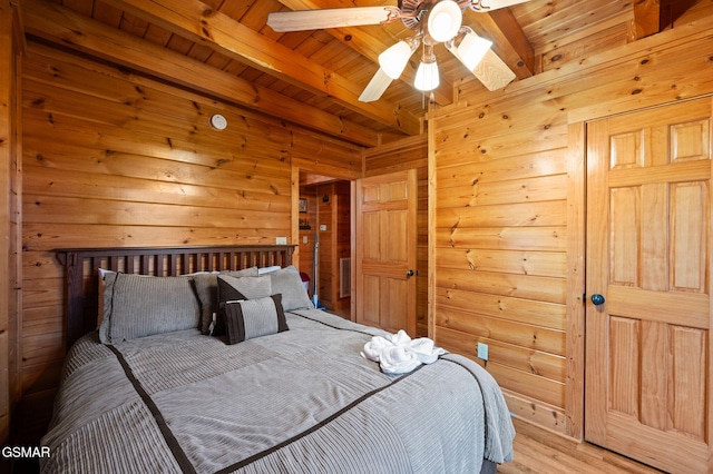 bedroom with beamed ceiling, wood ceiling, light hardwood / wood-style flooring, and wood walls