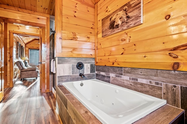 bathroom with lofted ceiling, a relaxing tiled tub, wood-type flooring, wooden ceiling, and wood walls