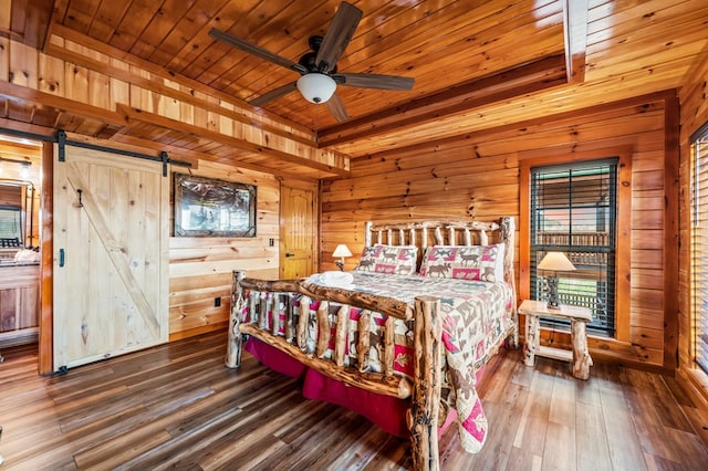 bedroom featuring dark wood-type flooring, a barn door, ceiling fan, and wood walls