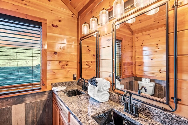 bathroom featuring wooden walls, lofted ceiling, vanity, wood ceiling, and toilet