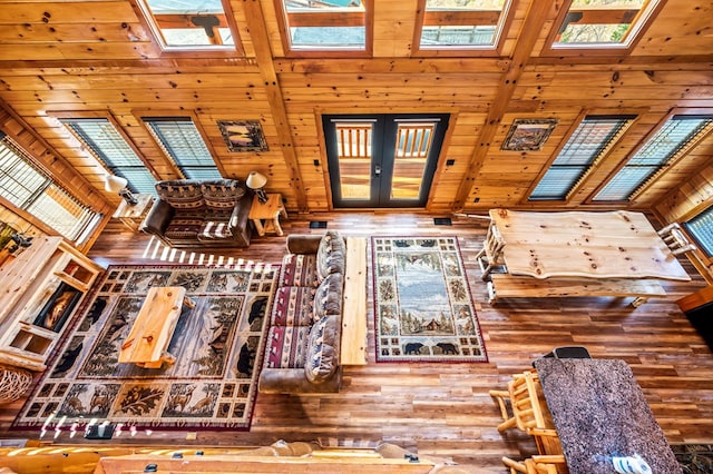 interior space with french doors, a healthy amount of sunlight, wooden walls, and a high ceiling