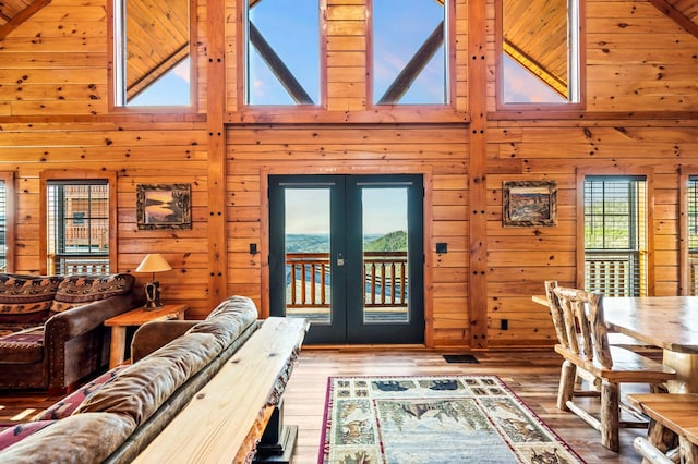 living room with high vaulted ceiling, french doors, and wood walls