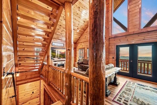 interior space featuring high vaulted ceiling, light wood-type flooring, french doors, beamed ceiling, and wood walls