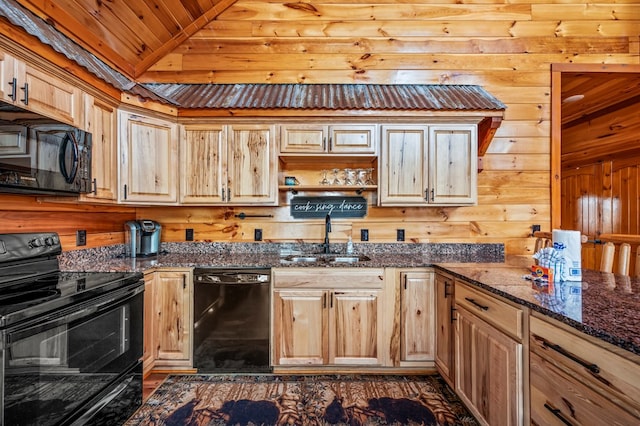 kitchen featuring lofted ceiling, sink, wood walls, dark stone counters, and black appliances