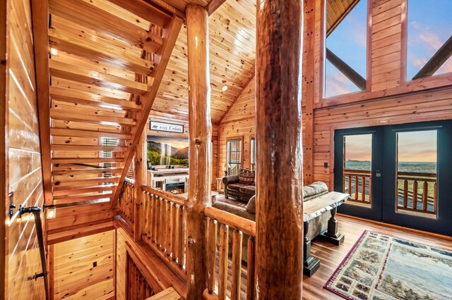 interior space with high vaulted ceiling, light hardwood / wood-style floors, french doors, beamed ceiling, and wood walls