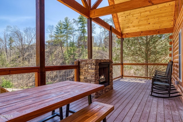 wooden terrace featuring an outdoor stone fireplace and outdoor dining area