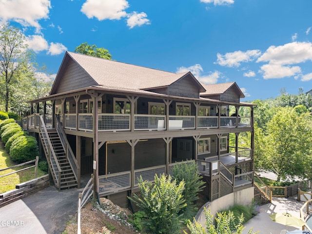 rear view of property with stairs, a balcony, fence, and a shingled roof