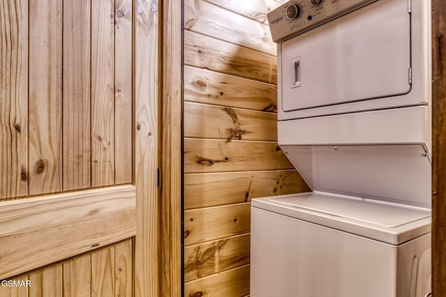 laundry area with estacked washer and dryer and wooden walls