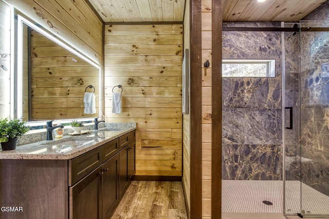 bathroom with wood walls, a stall shower, double vanity, wood finished floors, and wooden ceiling