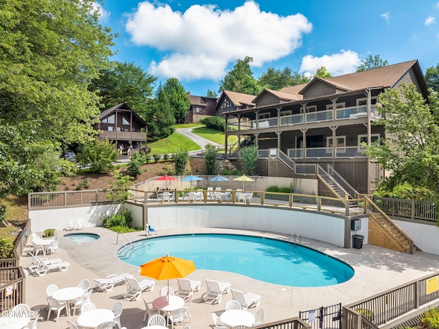 community pool with stairs, fence, a patio, and a community hot tub