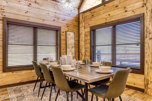 dining room with wooden walls, a chandelier, and wood finished floors
