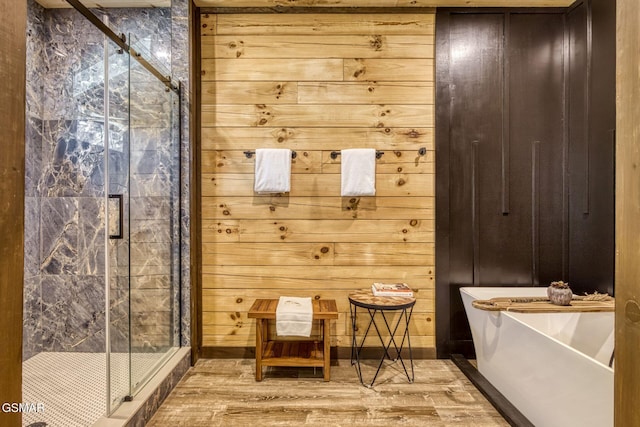 bathroom with wood finished floors, a stall shower, and a freestanding bath