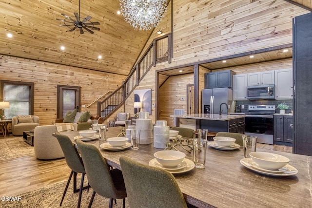 dining room featuring wooden walls, wooden ceiling, a high ceiling, light wood-type flooring, and recessed lighting
