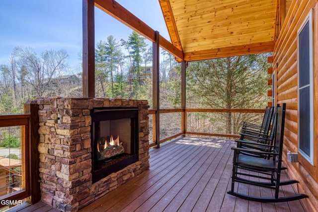 wooden terrace with an outdoor stone fireplace