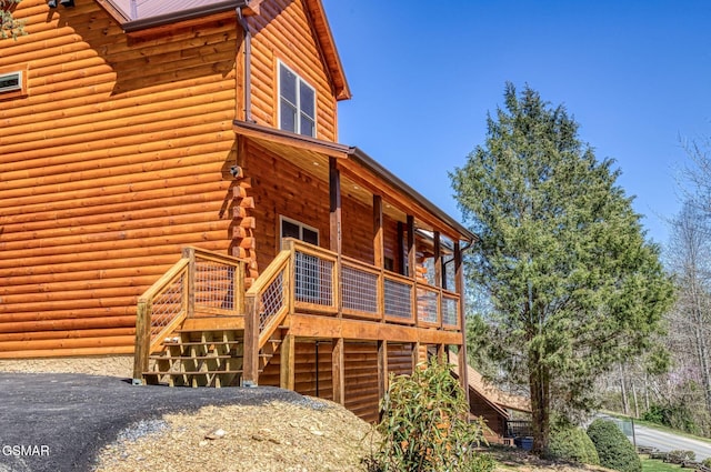view of side of home featuring log exterior, a deck, and stairs