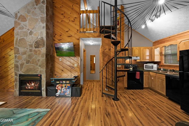 1503 Squirrel Nest Way, Sevierville, TN 37876 - kitchen with black appliances, wood finished floors, high vaulted ceiling, dark countertops, and a stone fireplace