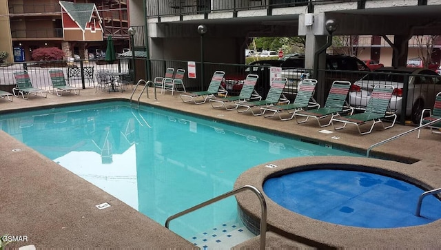 community pool with a patio area, fence, and a community hot tub