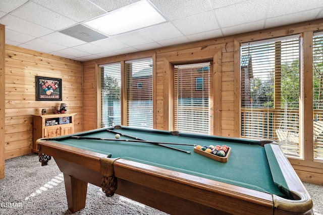 game room with a paneled ceiling, plenty of natural light, carpet floors, and wood walls