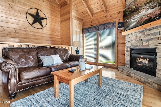 living room with wooden ceiling, a stone fireplace, hardwood / wood-style floors, and wood walls