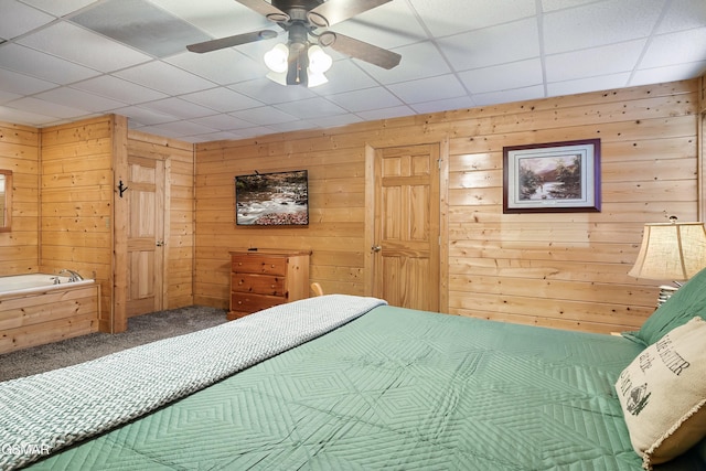 carpeted bedroom featuring wooden walls and ceiling fan