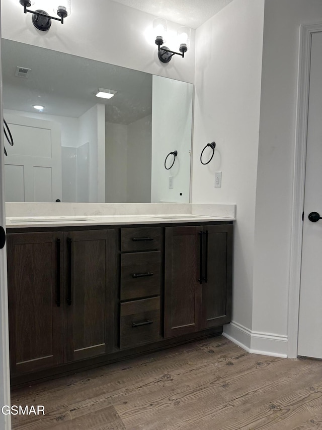 bathroom featuring visible vents, baseboards, wood finished floors, and vanity