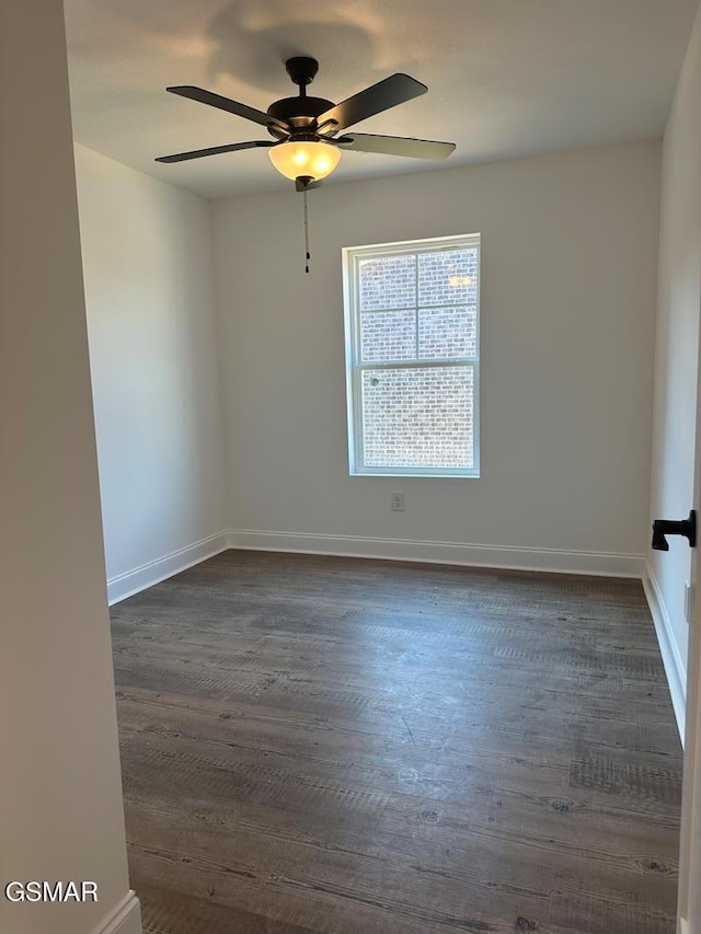empty room with ceiling fan, dark wood finished floors, and baseboards