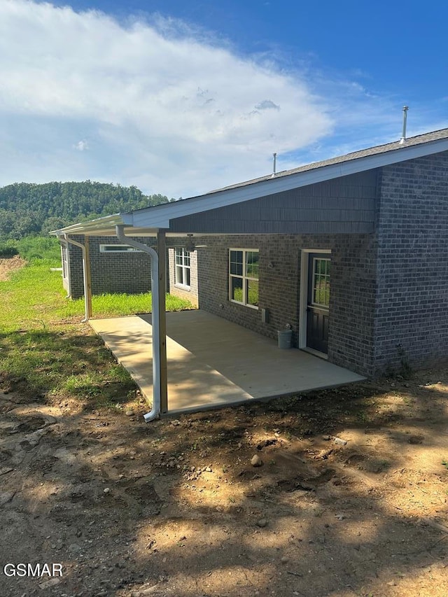 back of house with brick siding and a patio area