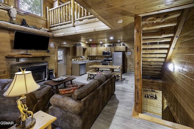 living room with wood walls, light hardwood / wood-style flooring, wooden ceiling, and sink