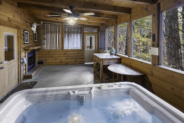 unfurnished sunroom featuring beamed ceiling, ceiling fan, wood ceiling, and a hot tub