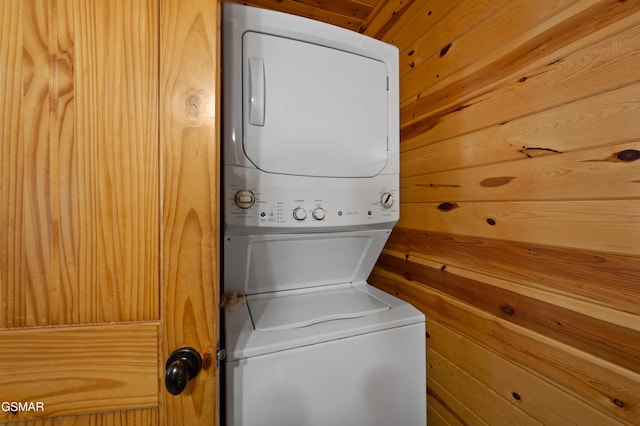 laundry area with stacked washer and clothes dryer and wooden walls