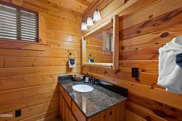 bathroom with a healthy amount of sunlight, vanity, and wooden walls