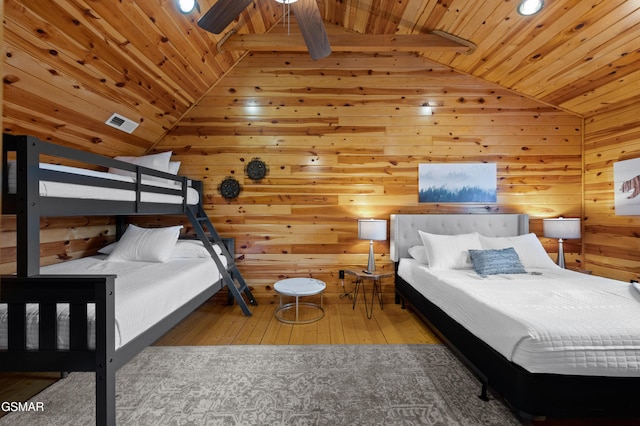 bedroom with vaulted ceiling, wood walls, light hardwood / wood-style floors, and wooden ceiling