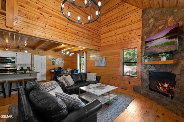 living room with a stone fireplace, wood ceiling, wooden walls, and light hardwood / wood-style flooring