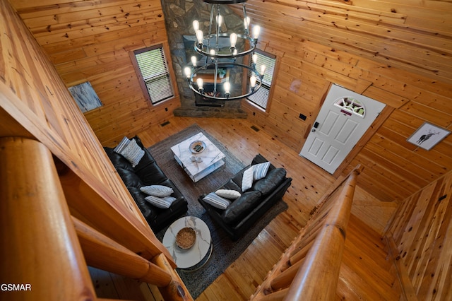 living room featuring wood walls, high vaulted ceiling, and an inviting chandelier