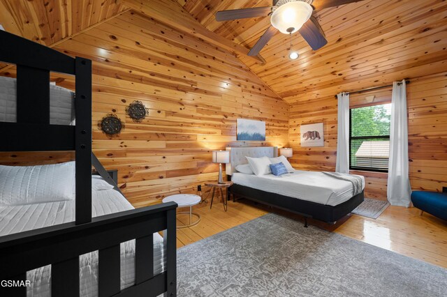 bedroom featuring wood ceiling, ceiling fan, light hardwood / wood-style floors, lofted ceiling, and wood walls