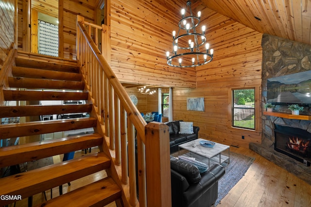 living room with wood walls, wooden ceiling, a fireplace, a notable chandelier, and wood-type flooring