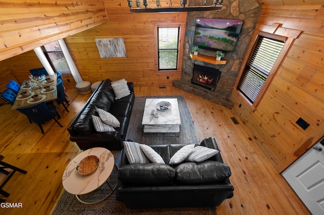 living room with a stone fireplace and wood walls