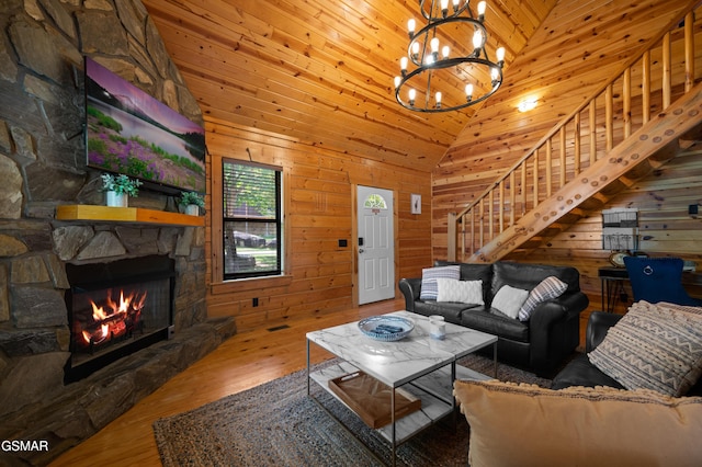 living room featuring high vaulted ceiling, wooden ceiling, hardwood / wood-style floors, a stone fireplace, and wood walls