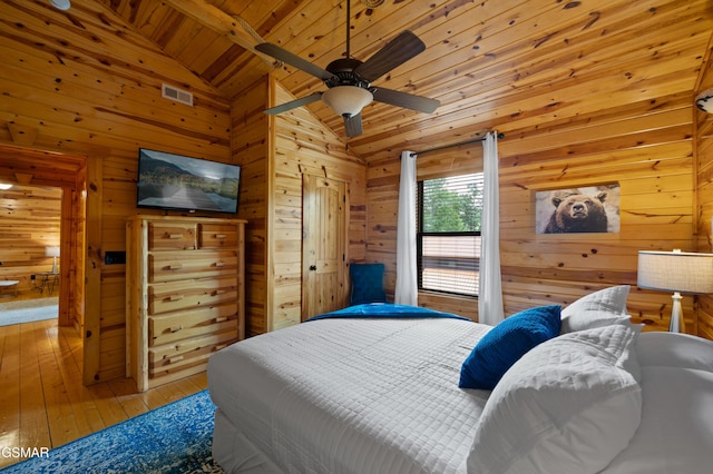 bedroom with ceiling fan, wood walls, lofted ceiling, wood ceiling, and hardwood / wood-style flooring