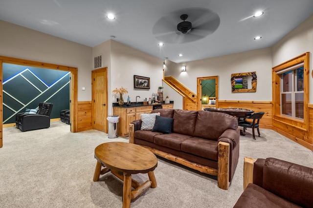 living room featuring wet bar, wainscoting, visible vents, and light colored carpet