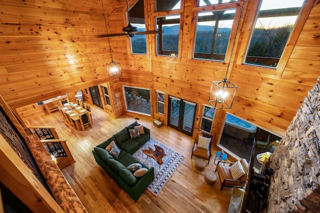 unfurnished living room with stairs, wooden walls, hardwood / wood-style floors, and ceiling fan with notable chandelier