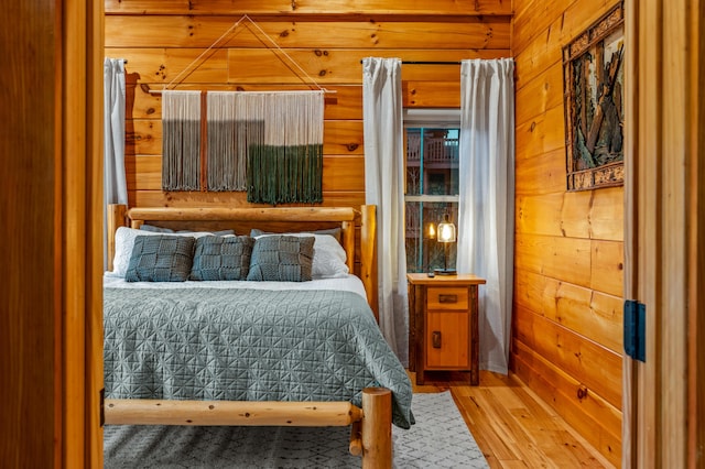 bedroom featuring light wood-style flooring and wooden walls